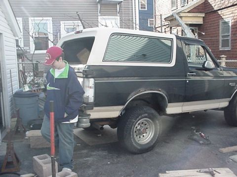 1993 Ford Bronco - A dark green and white 1993 Ford Bronco is parked in a driveway with a person standing nearby.