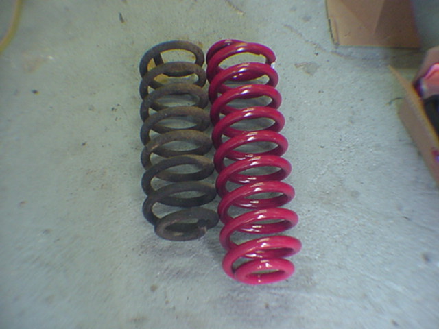 Two coil springs side by side, one rusty and one painted red
