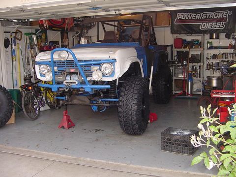 1971 Ford Bronco - This 1971 Ford Bronco is parked in a garage, a prominent blue roll cage and winch on the front bumper.