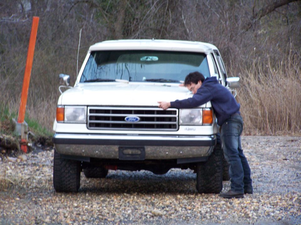 Man hugging the grille of a white 1987 Ford F-Series truck
