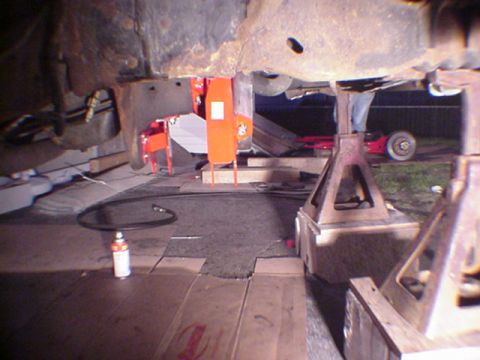 1993 Ford Bronco - Vehicle under repair, supported by jack stands, with tools and parts visible on the ground.