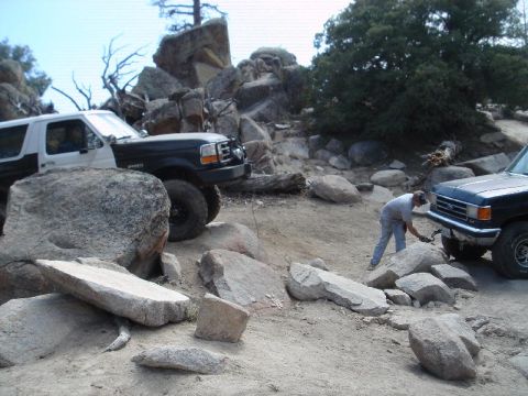 1994 Ford Bronco - Two SUVs, including a 1994 Ford Bronco, tackle a challenging rocky off-road path.