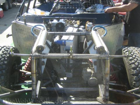 1990 Ford Bronco - front of a tube-chassis off-road racer shows its engine, intake, twin coilover shocks and a mesh grille panel.