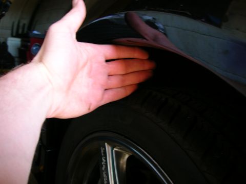 1994 Ford Probe - A hand is shown checking the clearance between the tire and the wheel well of a vehicle.