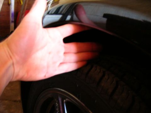 1994 Ford Probe - A hand is shown inside the wheel well of a black car, near the tire and rim.