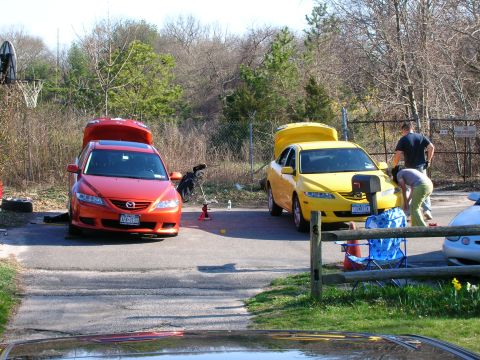 1994 Ford Probe - Two sedans, one red and one yellow, are parked with their trunks open, suggesting maintenance or loading activities.