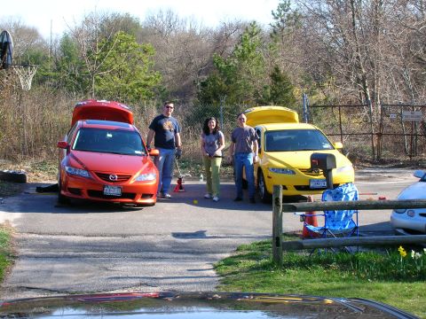 1994 Ford Probe - Two Mazda 6 sedans are parked outside with their trunks open, and three people are standing between them.