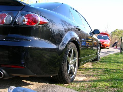 1994 Ford Probe - A black sedan is parked on the side of the road, with another red car visible in the distance.