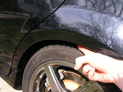 1994 Ford Probe - Checking tire clearance in the rear wheel well of a black car.