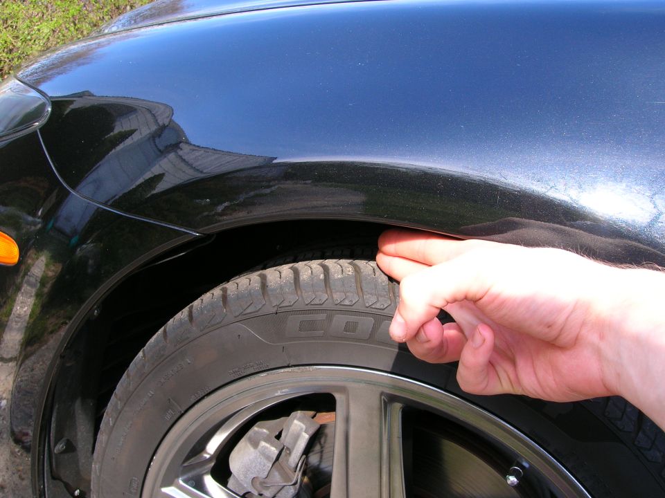 hand checking gap between tire and fender on black car