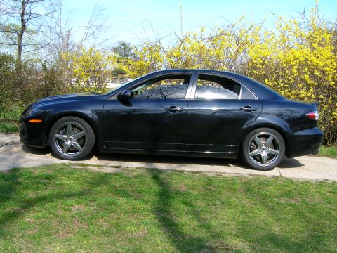 1994 Ford Probe - Side view of a black sedan with aftermarket wheels parked outdoors.