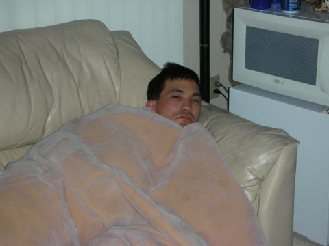1992 Ford Crown Victoria - A man is asleep on a couch, with a television set visible in the background.
