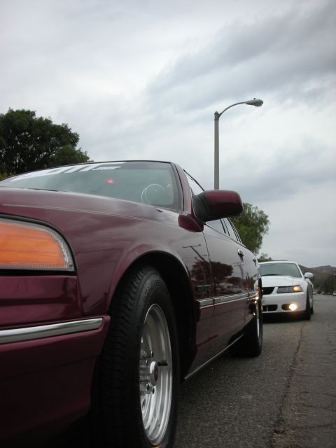 1992 Ford Crown Victoria - A maroon 1992 Ford Crown Victoria is parked on the side of the road with a white coupe behind it.
