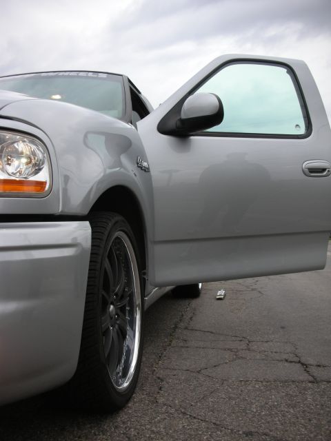 1992 Ford Crown Victoria - A silver pickup truck is shown with its driver's door ajar, revealing the interior and a portion of the front wheel.