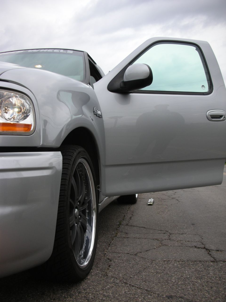Silver pickup truck, driver's door open, front wheel and fender visible