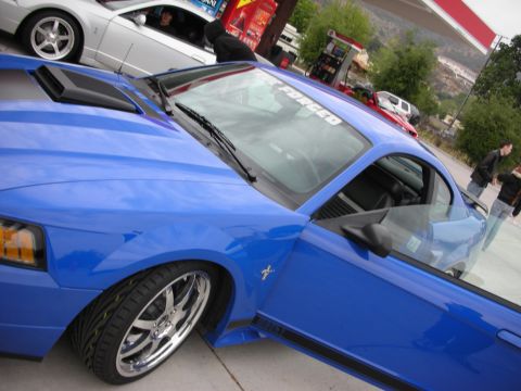 1992 Ford Crown Victoria - A blue Ford Mustang is parked at a gas station with another Mustang in the background.