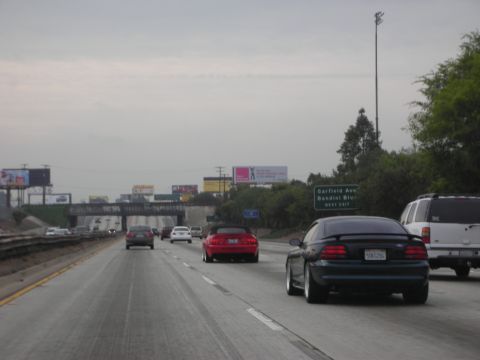 1992 Ford Crown Victoria - Traffic moves along a highway with billboards and an overpass visible.