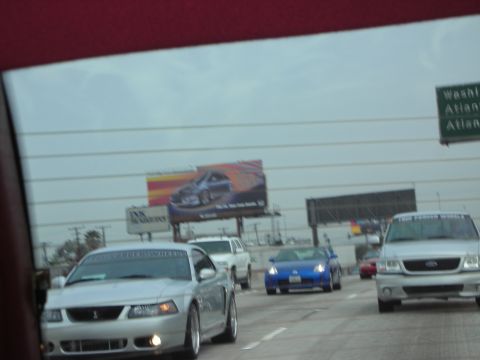 1992 Ford Crown Victoria - A silver Ford Mustang drives down the highway with other vehicles around it.