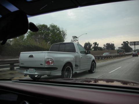 1992 Ford Crown Victoria - Silver 1999 Ford F-150 SVT Lightning pickup truck seen from behind on the highway.