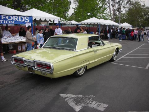1992 Ford Crown Victoria - A 1965 Ford Thunderbird is displayed at a car show with tents and people in the background.