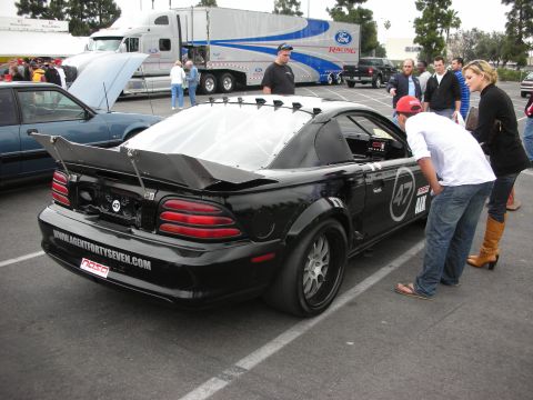 1992 Ford Crown Victoria - Modified black Ford Mustang at an event, with a Ford Racing truck visible in the background.
