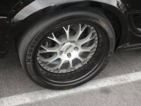 1992 Ford Crown Victoria - A close-up shot focuses on a customized wheel and tire assembly on a black vehicle, highlighting aftermarket modifications.
