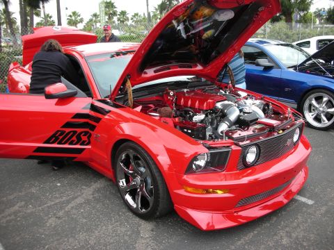 1992 Ford Crown Victoria - A red Ford Mustang with its hood open displays a supercharged engine and black side decals.