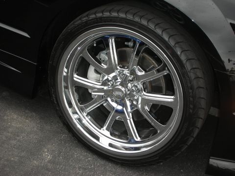 1992 Ford Crown Victoria - Close-up of a shiny chrome wheel and tire on a dark vehicle.