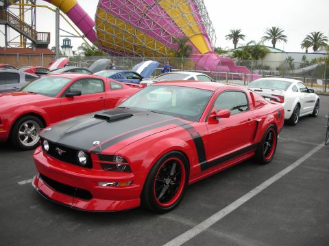 1992 Ford Crown Victoria - A red 2005 Ford Mustang GT with black racing stripes and Boss 302 badging is parked at an outdoor event.