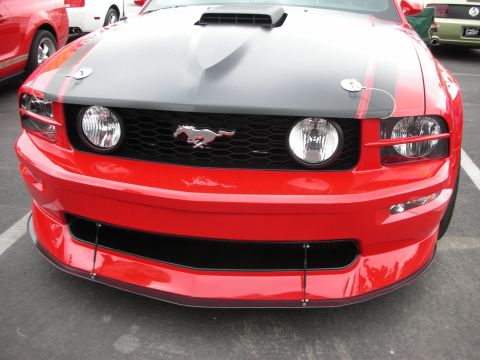 1992 Ford Crown Victoria - Front view of a red Ford Mustang, showing the grille, headlights, and hood details. Another vehicle is parked nearby.