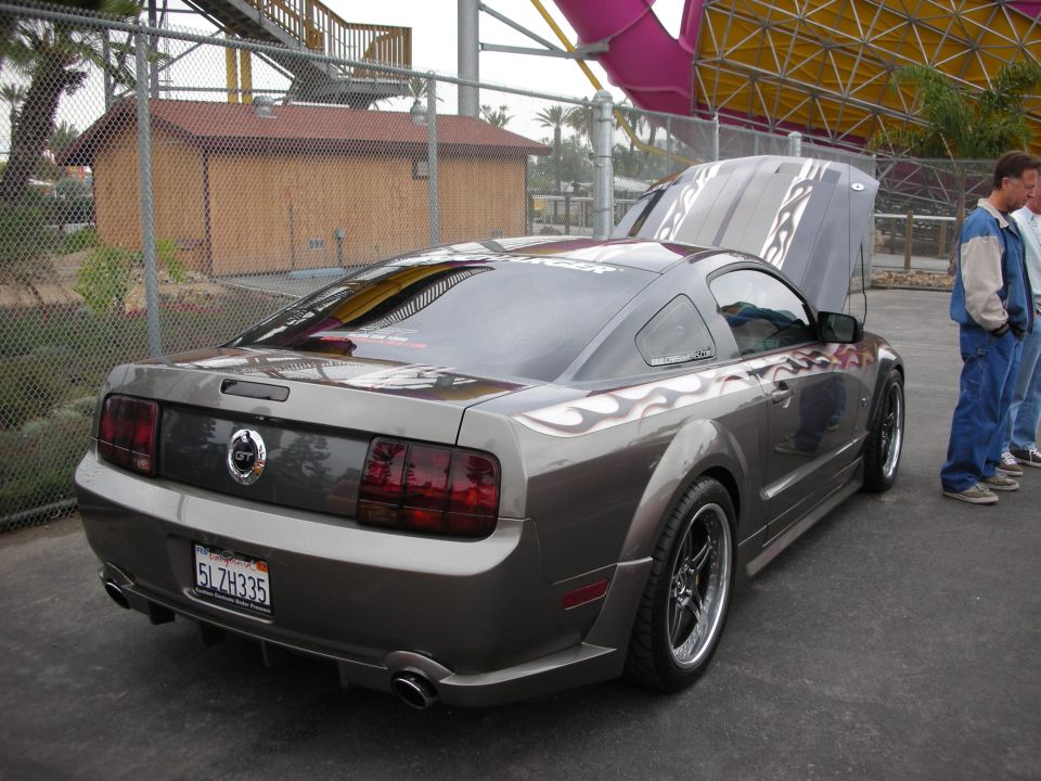 Gray Ford Mustang coupe with flame decals, hood open, parked outdoors