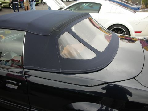 1992 Ford Crown Victoria - The convertible top of a dark car is shown from the side, with other vehicles in the background.