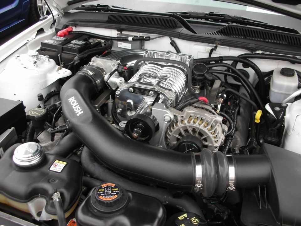 Engine bay with a polished supercharger and black Roush intake tubing