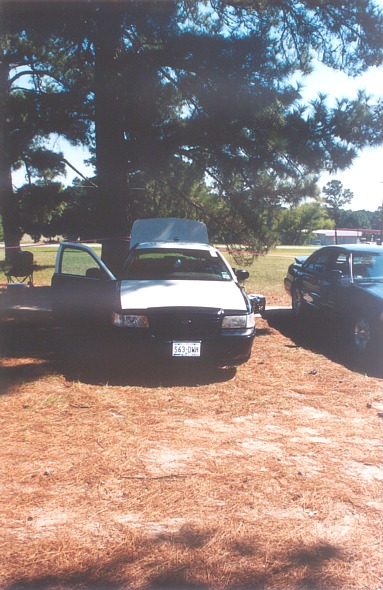 2002 Ford Crown Victoria - A white and black 2002 Ford Crown Victoria is parked with its hood and driver door open, next to another dark-colored vehicle.
