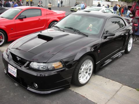 1992 Ford Crown Victoria - A black Ford Mustang is parked at a car show, with a red Mustang to its left.