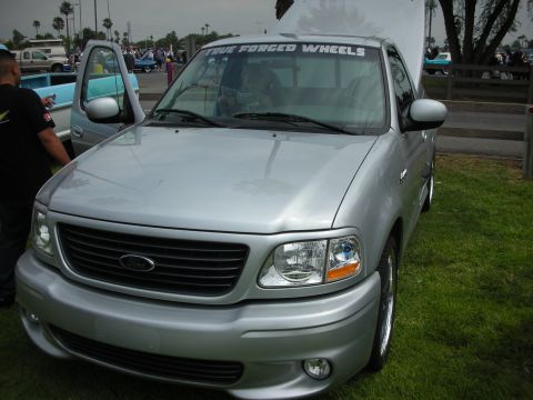 1992 Ford Crown Victoria - Silver 1999 Ford F-150 Lightning pickup truck with 'TRUE FORGED WHEELS' banner on windshield.