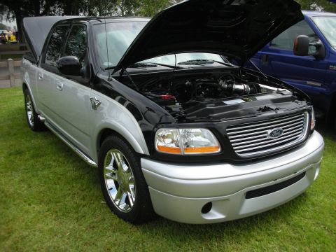 1992 Ford Crown Victoria - Customized 1999 Ford F-150 SVT Lightning pickup truck with its hood open at a car show.