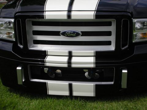 1992 Ford Crown Victoria - A black Ford truck with white racing stripes on the grille and bumper is parked on grass.