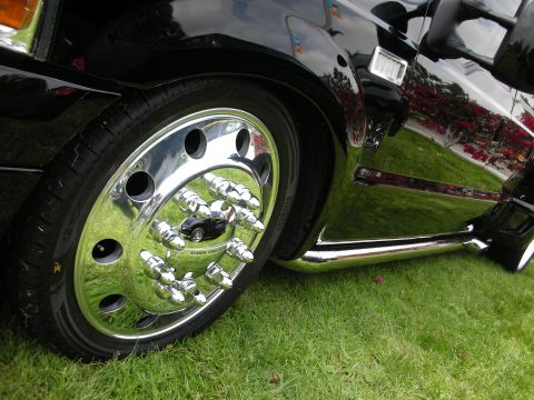 1992 Ford Crown Victoria - Close-up of a black truck's side, highlighting its shiny chrome wheels and trim against a grassy background.