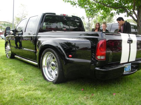 1992 Ford Crown Victoria - Black Ford F-350 Super Duty pickup truck with dual rear wheels and white racing stripes on the tailgate.