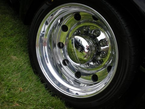 1992 Ford Crown Victoria - A polished chrome wheel and tire sit on a grassy surface, with reflections visible in the hubcap.