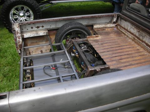 1992 Ford Crown Victoria - Custom pickup truck bed with modified fuel tank and suspension components, with another vehicle's wheel in view.