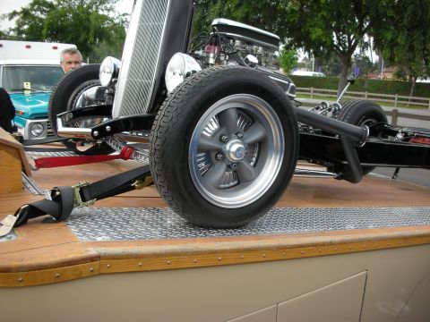 1992 Ford Crown Victoria - Hot rod chassis being transported on a trailer, with a turquoise Ford truck in the background.