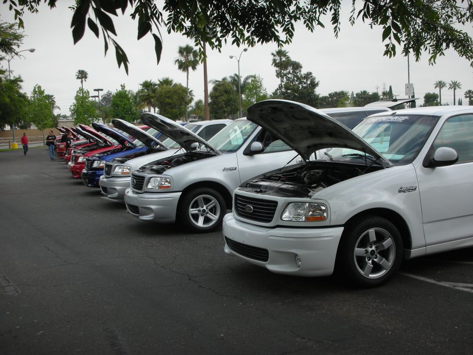 Several Ford F-150 Lightning trucks parked in a row with hoods open