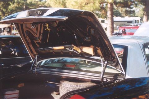 2002 Ford Crown Victoria - The trunk of a car is open, revealing the spare tire and storage area, with other vehicles in the background.