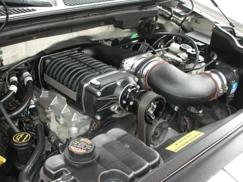 1992 Ford Crown Victoria - Close-up of a vehicle's engine bay, highlighting a prominent black supercharger and associated plumbing.