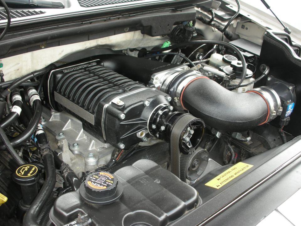 Engine bay with a black supercharger and intake piping