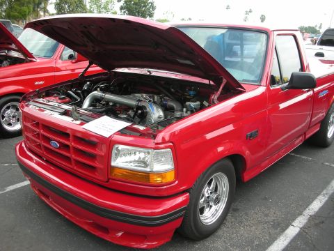 1992 Ford Crown Victoria - A red 1992 Ford F-150 pickup truck is displayed with its hood open, revealing a modified engine.