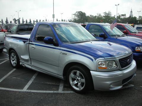 1992 Ford Crown Victoria - Customized 1999 Ford F-150 Lightning pickup truck with a two-tone silver and blue paint scheme and flame graphics.