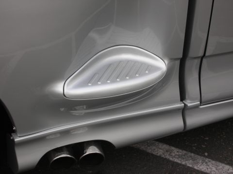 1992 Ford Crown Victoria - Close-up of a silver vehicle's rear fender vent and dual exhaust pipes.